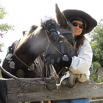 woman in hat with black horse