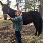 woman in a green shirt petting a horse